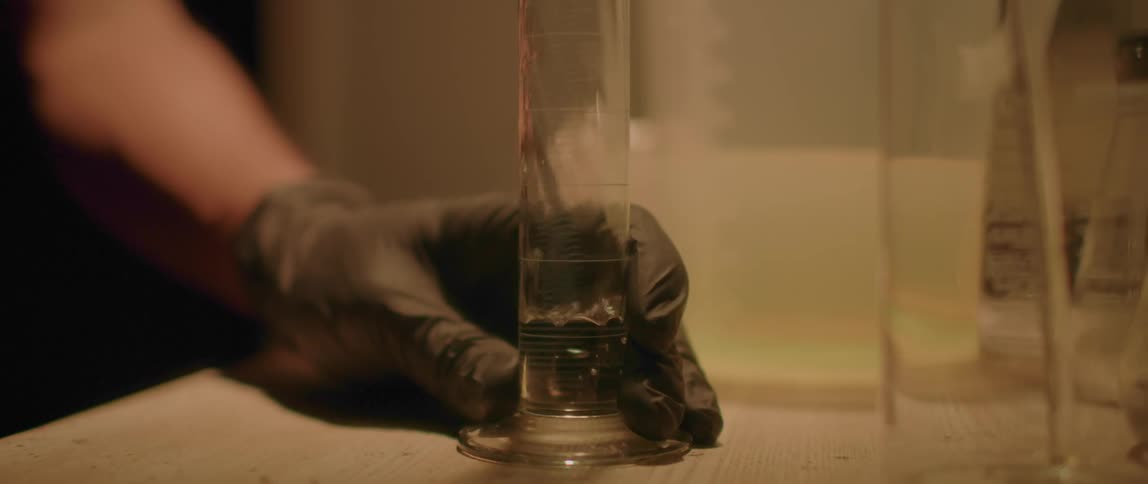 Photographer preparing developing liquid on a graduated cylinder in a dark room