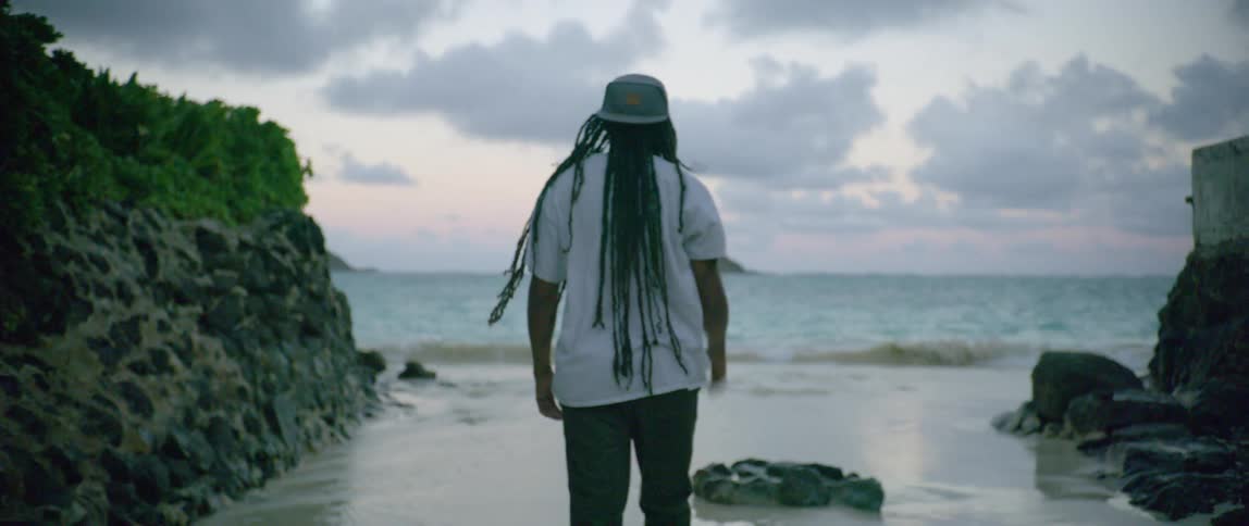A black male with dreadlocks walking on a beach
