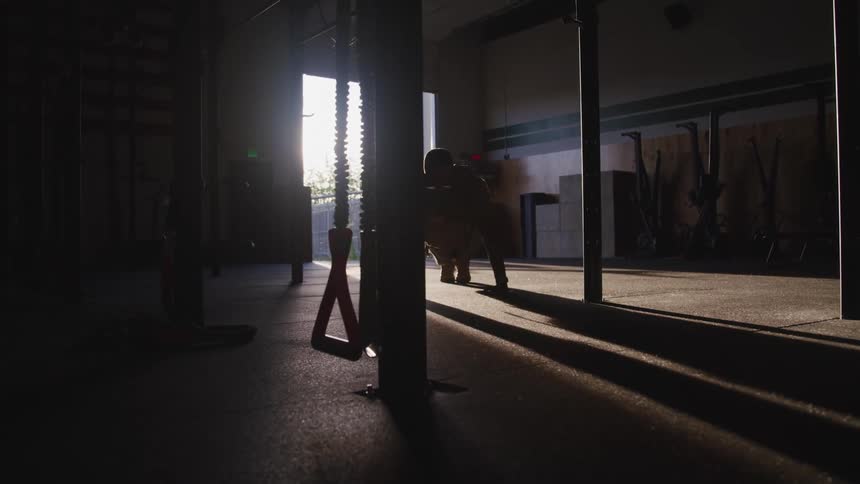 A man doing push ups inside of a training room with sunlight shining in from an open doorway