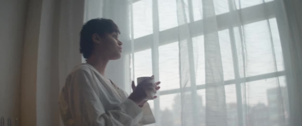 Woman drinking coffee while staring through the window