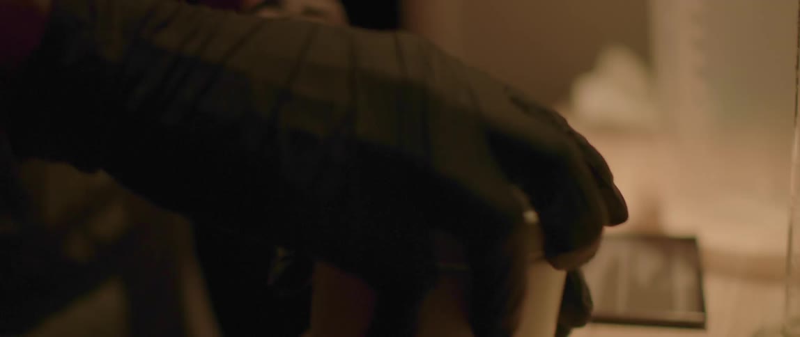 A person wearing black latex gloves unscrewing the lid of a cilindrical canister