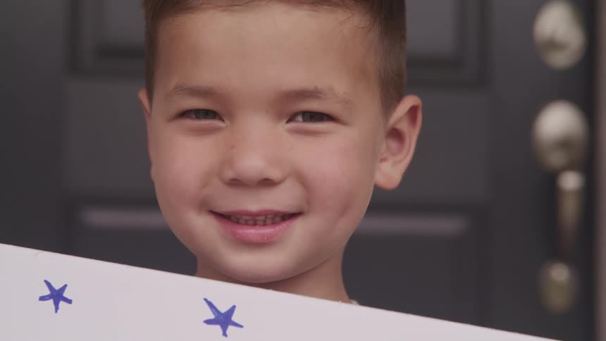 A child is standing by a door and smiling