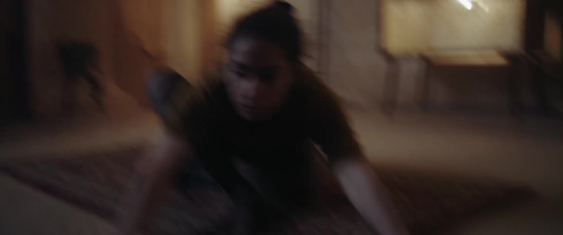 A woman rolls around on the ground in a dingy apartment as she does a modern dance
