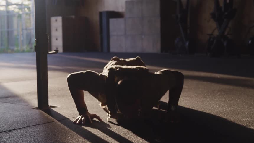 Man working out alone doing push ups while wearing a vest