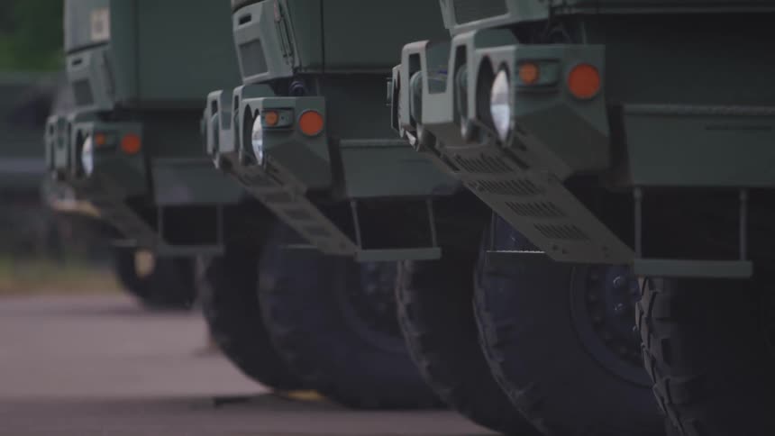 Green military vehicles parked on asphalt