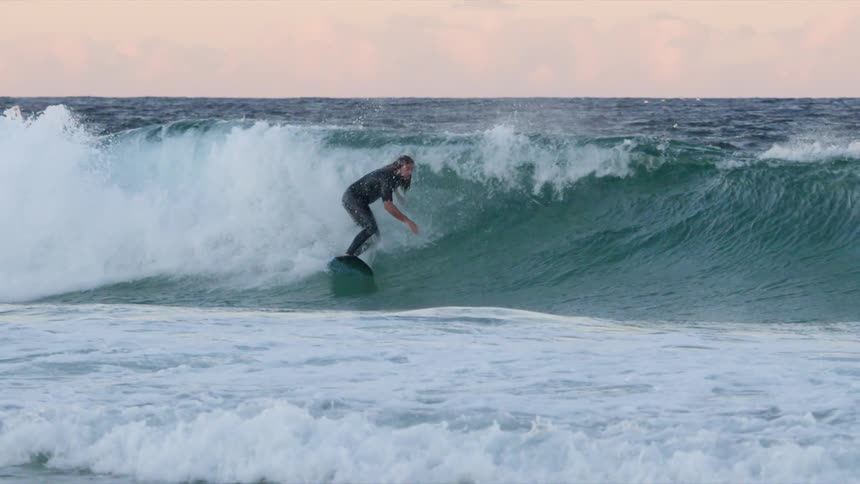 Male surfer riding huge wave on a cloudy day