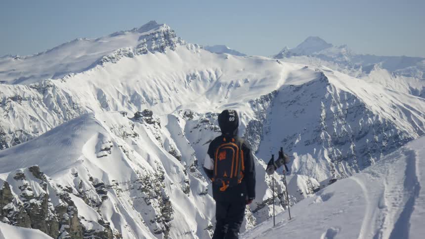 Person contemplating the mountain landspace at the summit of a mountain