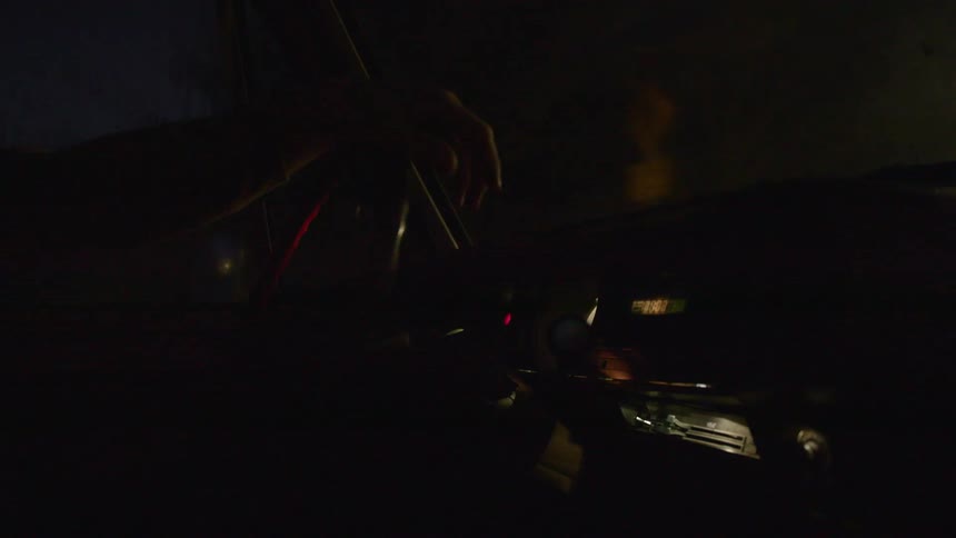 Silhouette of a person driving a car through a city street at night