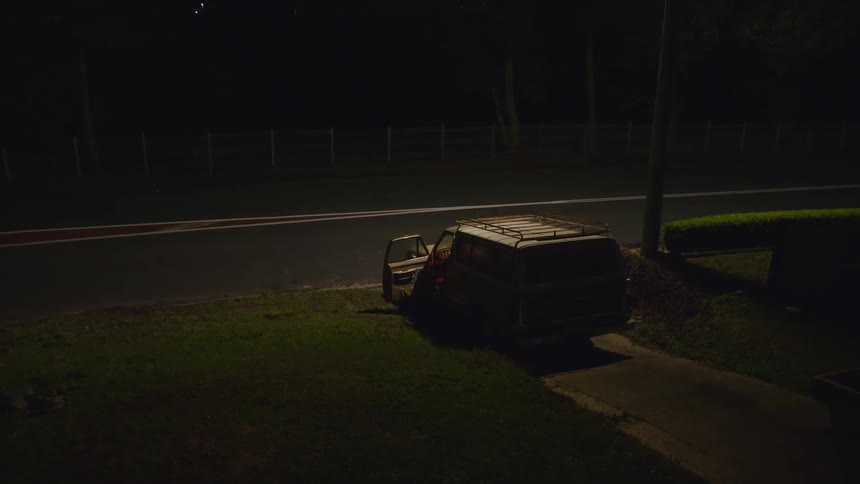 Man boarding a car parked on the driveway of a home at night