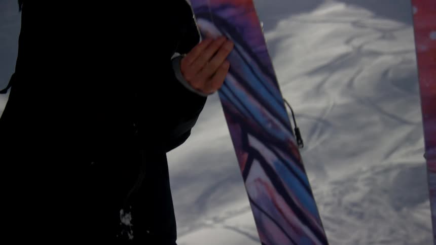 A man is examining his skis on the slope