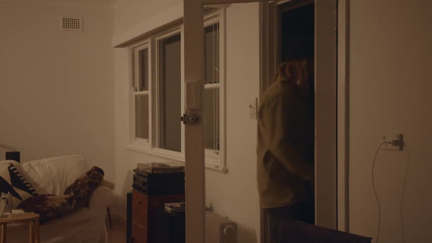 A man grabs a jacket opens the front door and exits his home