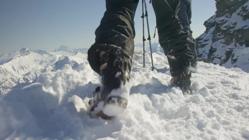 Person walks on snow in boots on top of a mountain