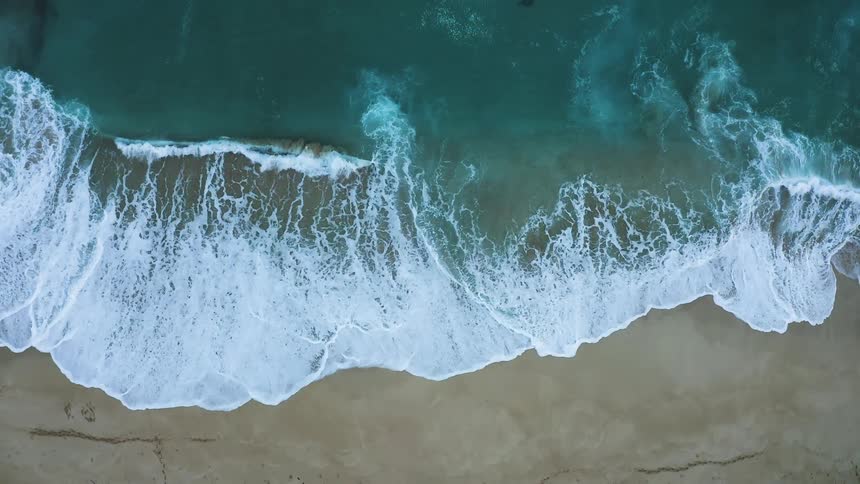 A beach with sand and waves of water
