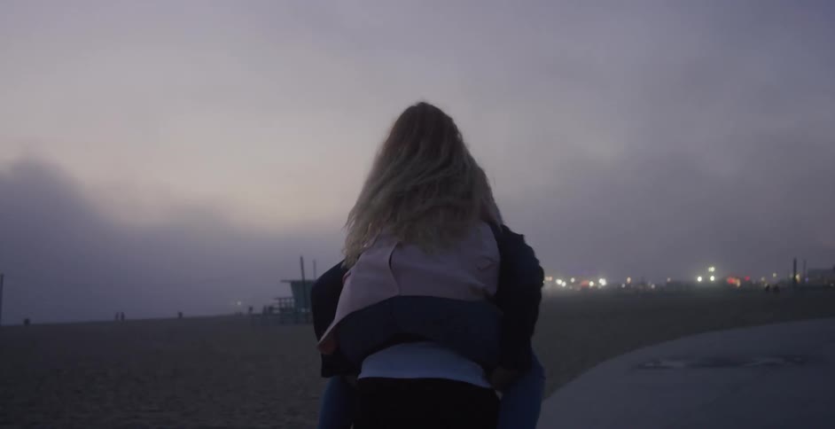 Couple running around while one piggybacks outside
