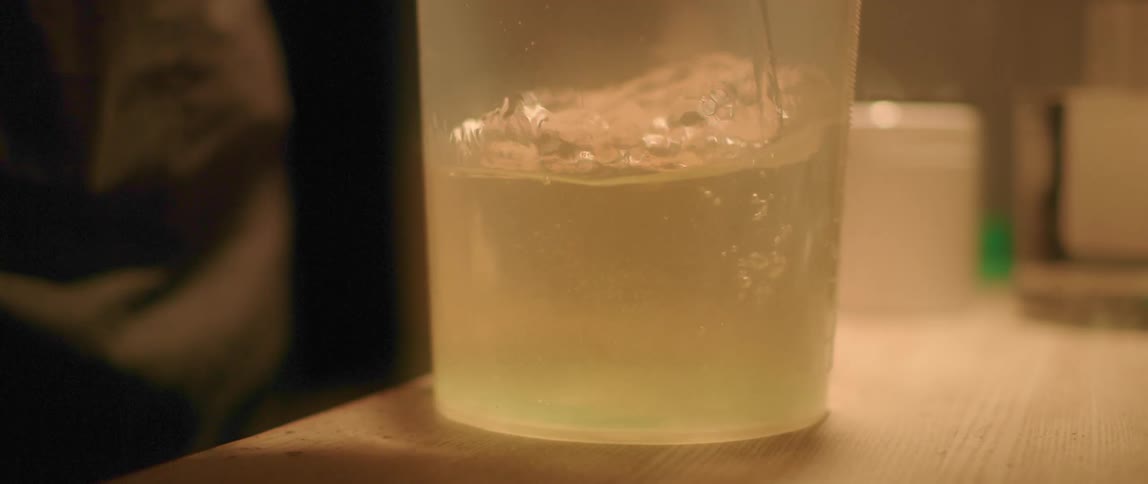 A person stirring water in a plastic pitcher with a glass stirrer