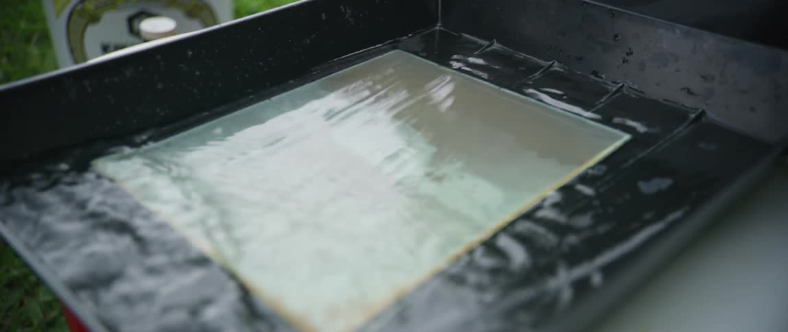 Photographer submerges a glass sheet to develop a vintage photograph