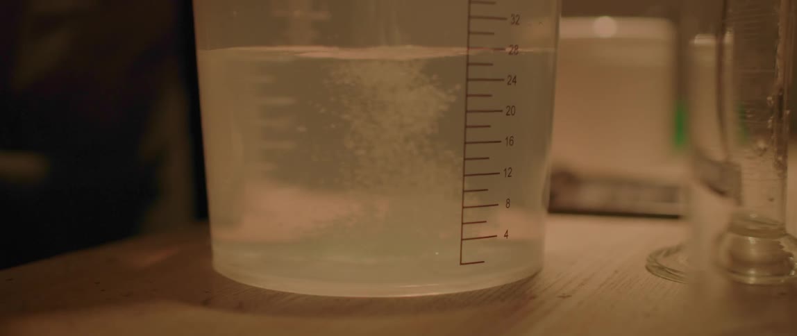 A container on a table with water and salt falling into it