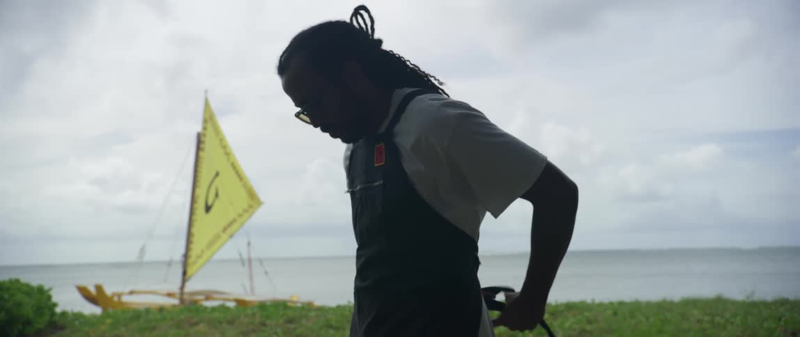 Man with braids and glasses wears black apron