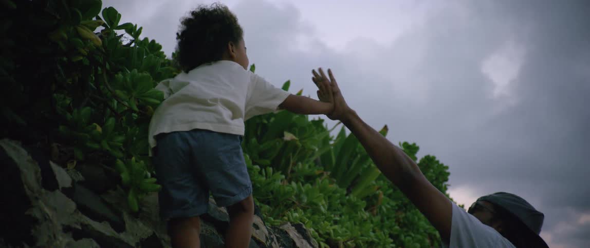 Father playing with his children next to the beach while the mother is holding a baby