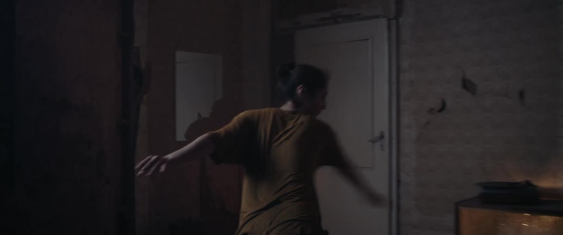 A young woman dances in a dilapidated room in a house