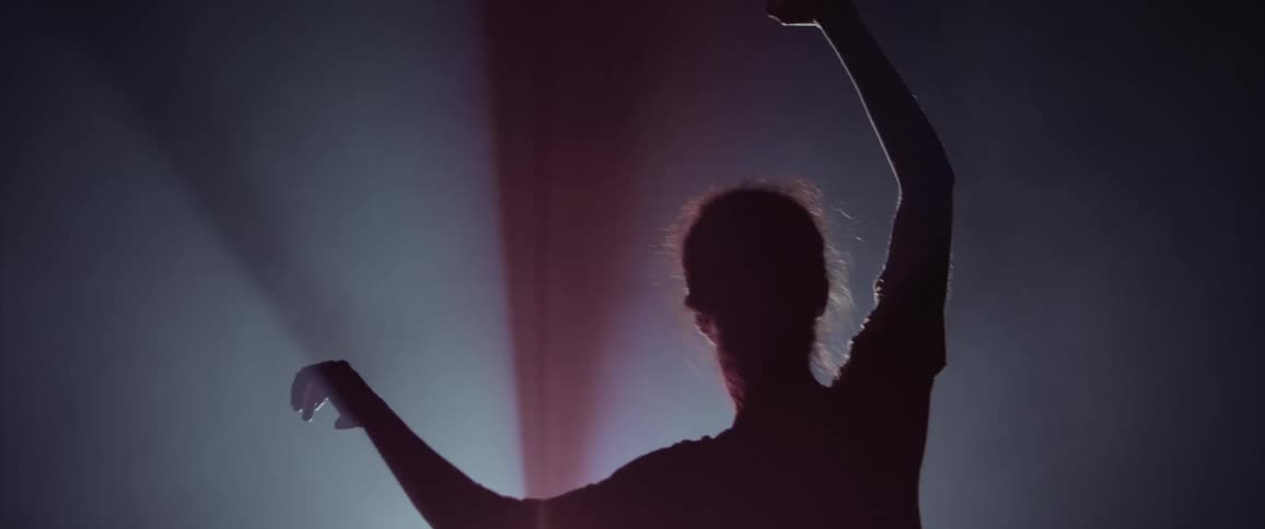 A person slowing moving their arms around in the dark in front of a strobe light