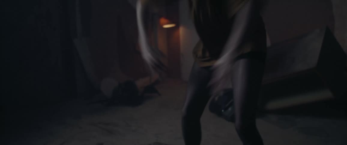 A young woman dances in a dilapidated room illuminated by flashing lights