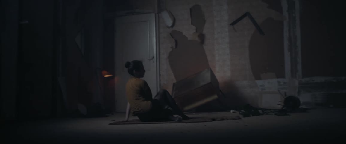 Woman performs on set with blinking light and damaged wallpaper