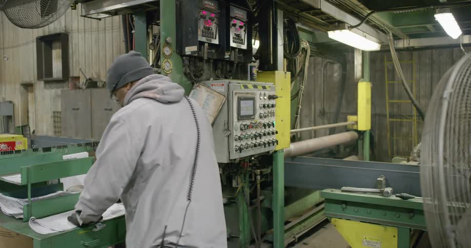 Worer operates machinery to weld metal profiles in a factory
