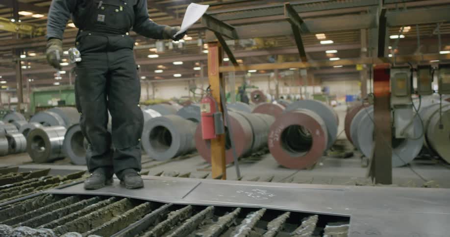 A metal worker marking the surface of a steel sheet on a factory in a warehouse