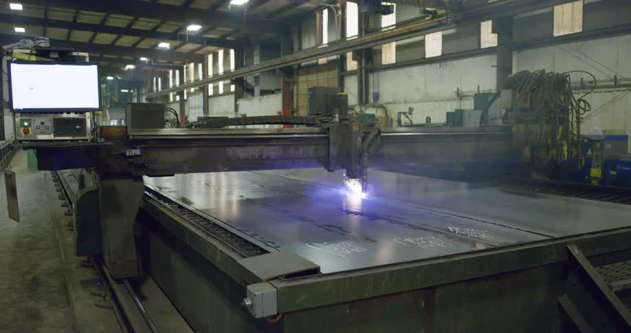 Computer controlled machine cuts across metal sheets in factory