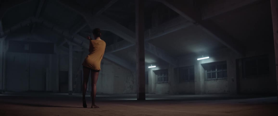 A female stretching and doing dance movements in an empty warehouse