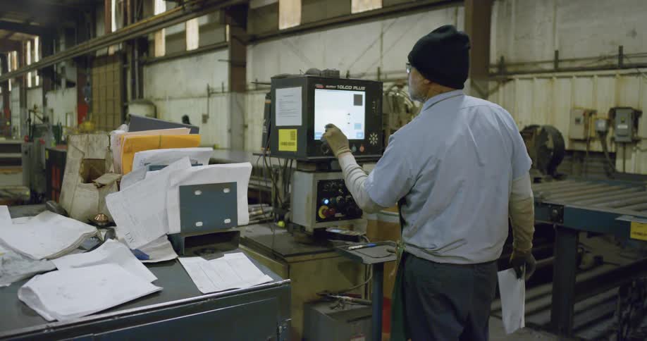 Worker operating machinery ina metal working factory inside a warehouse
