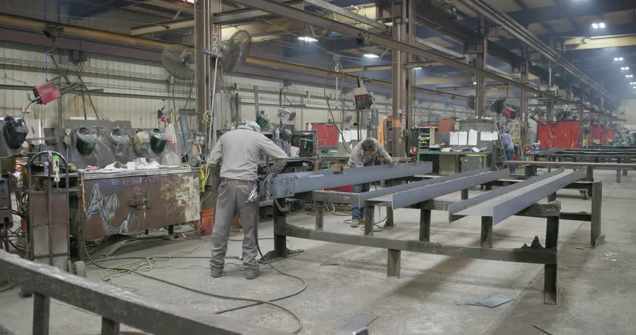 Two men are welding a piece of steel