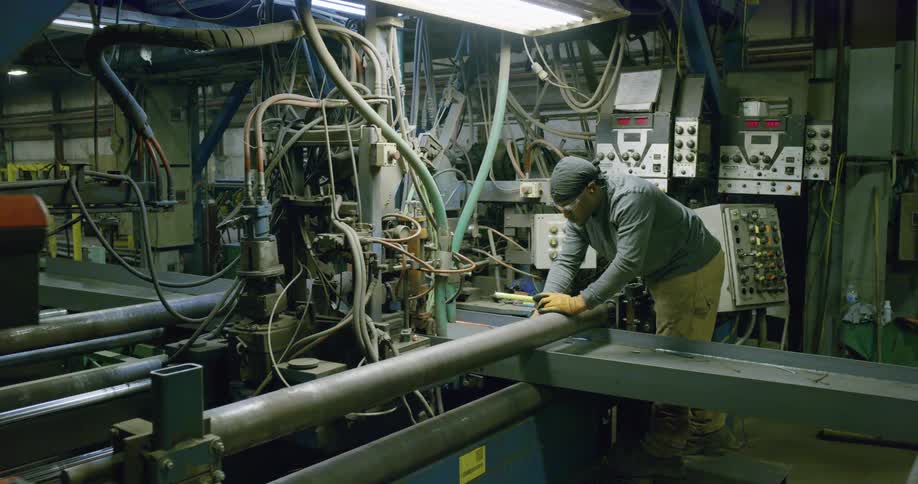 A man uses a measuring tape as he repairs a piece of machinery