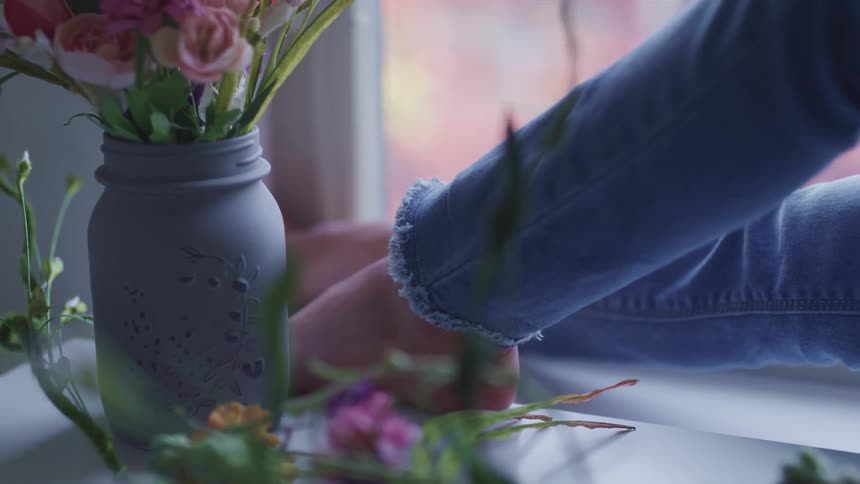 A panning shot of a person laying next to a plant