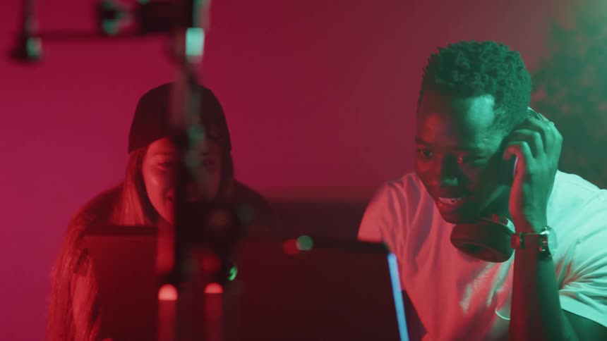 Black man and white woman working on a laptop at the recording studio