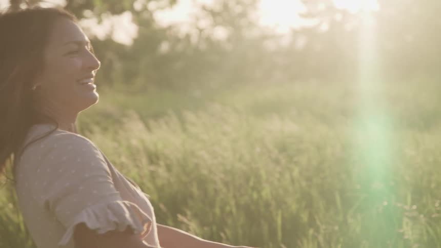 Mother and daughter happily playing over the tall green grass at sunset