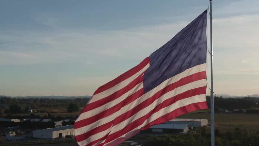 American flag on pole wavering in the wind on a cloudy day