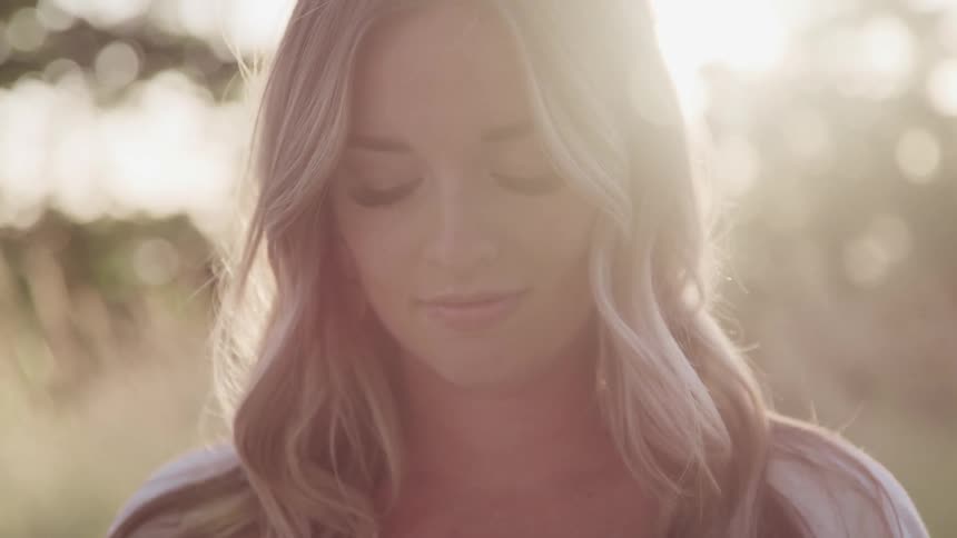 Young blonde woman facing the camera while looking down