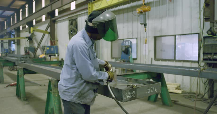 A man measures an angle with a speed square and bangs in place with a mallet
