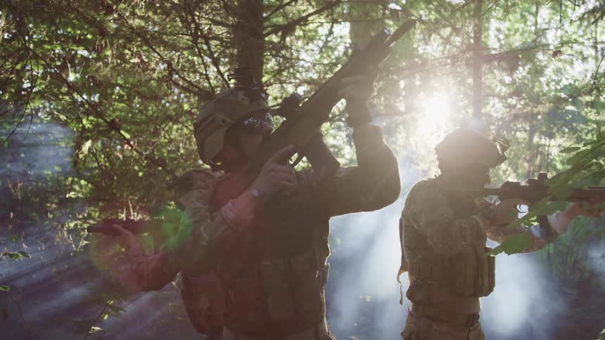 Military men in the middle of a forest pointing guns