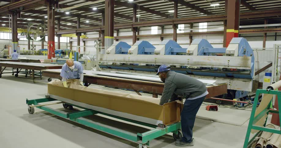 Two workers moving a sheet into a box
