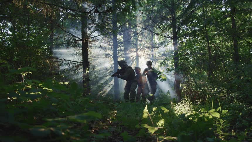 Three soldiers in the forest with guns drawn and the sun shining brightly behind them