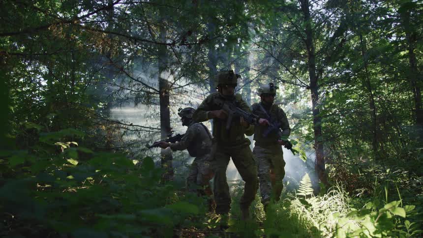 Military men walking through a forest together while holding guns