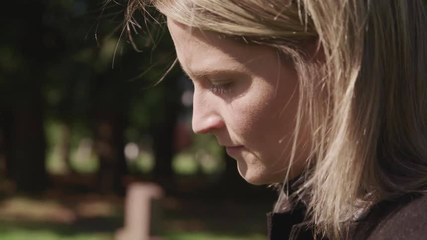 A woman is standing outdoors at a cemetary