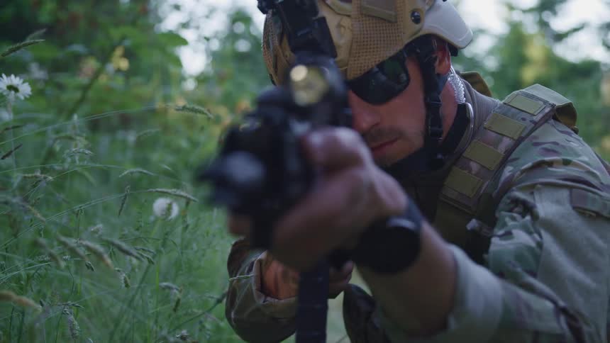 A man aiming a gun in a field