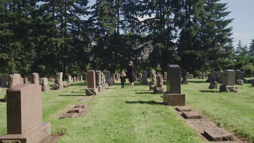 A woman and child walk next to one another in a cemetery