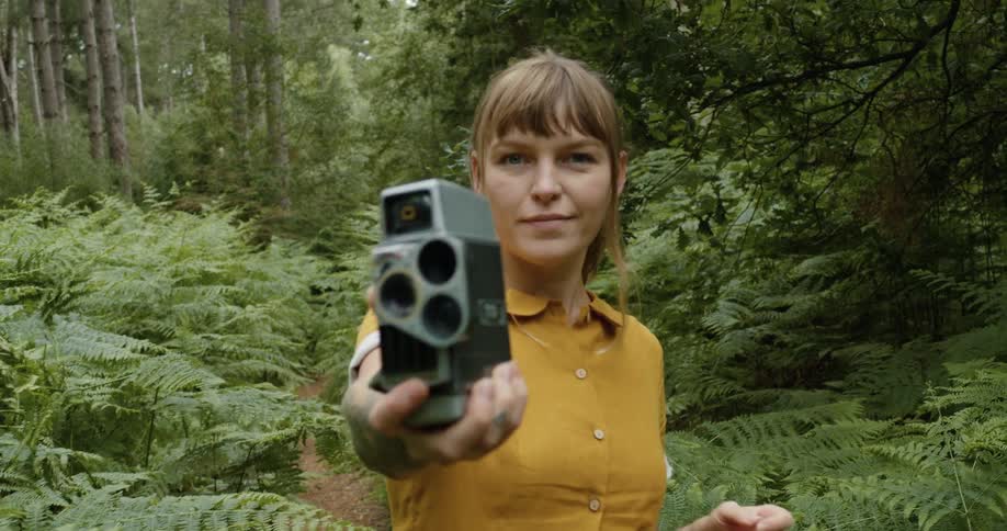 Young woman holding a vintage film camera in the woods