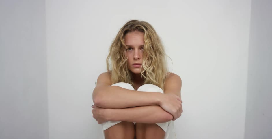 White woman sitting down alone with her head down in a sad way