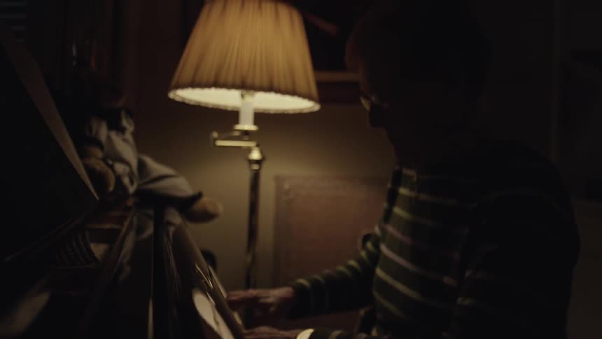 Older woman playing the piano in a dimly lit room
